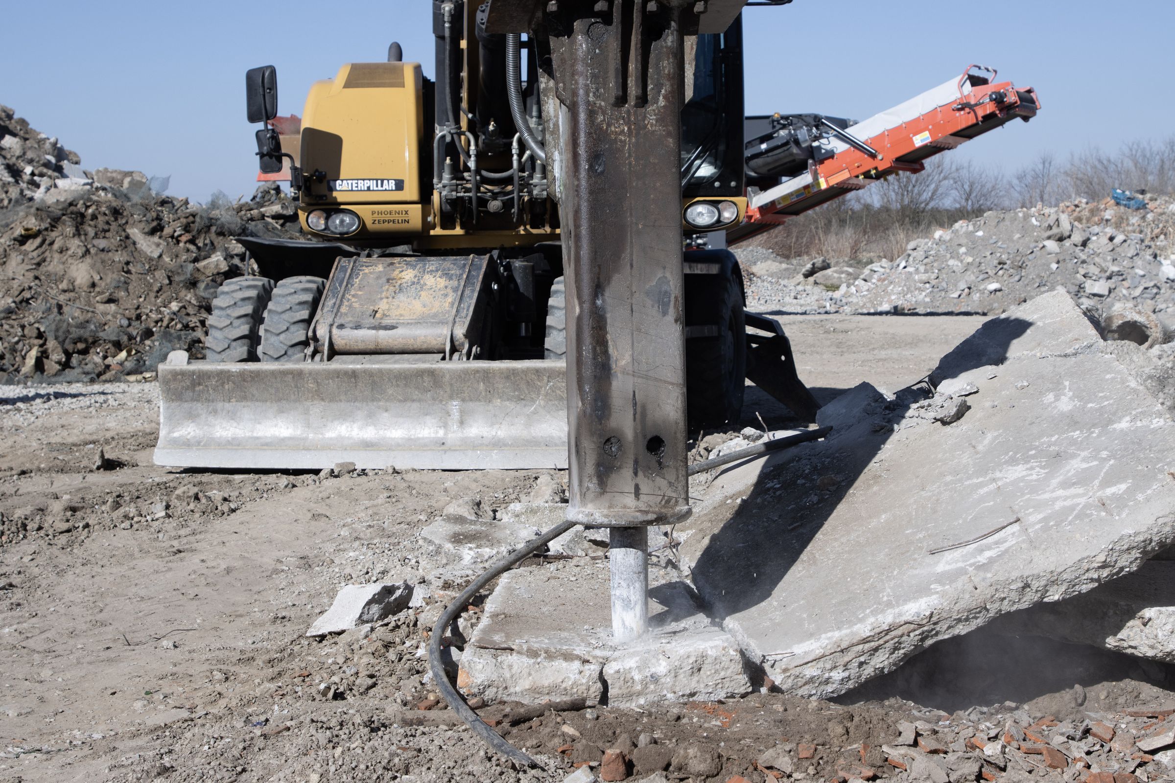 Rozbíjanie betónu hydraulickým kladivom na rýpadle CAT