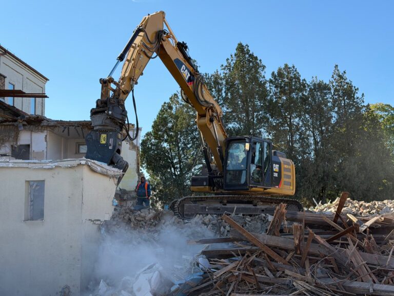Rýpadlo CAT 320E s drviacimi kliešťami pri búraní budovy