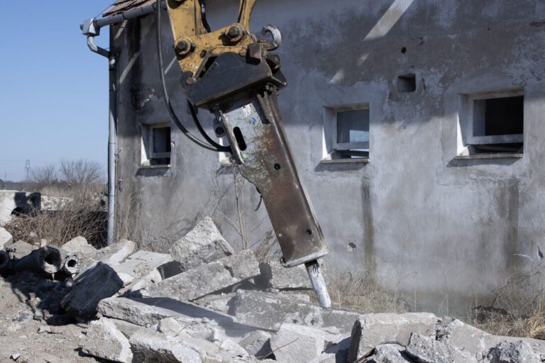 Hydraulické kladivo búra betón pri stene objektu
